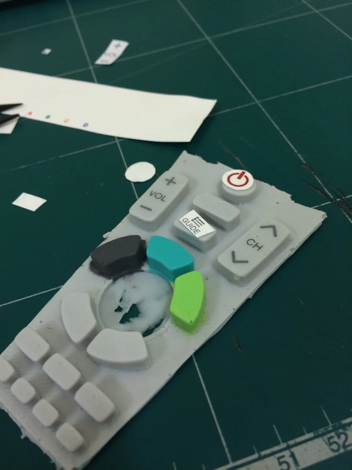 Painted buttons laid out on a cutting mat with printed labels