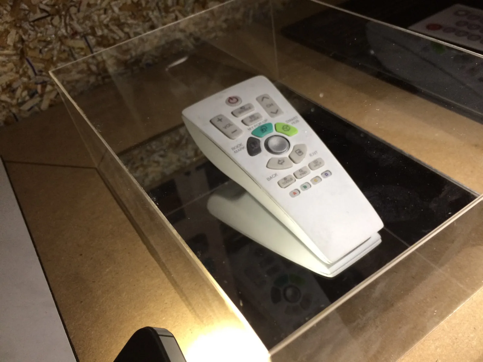 Uni remote presented inside a clear acrylic display case